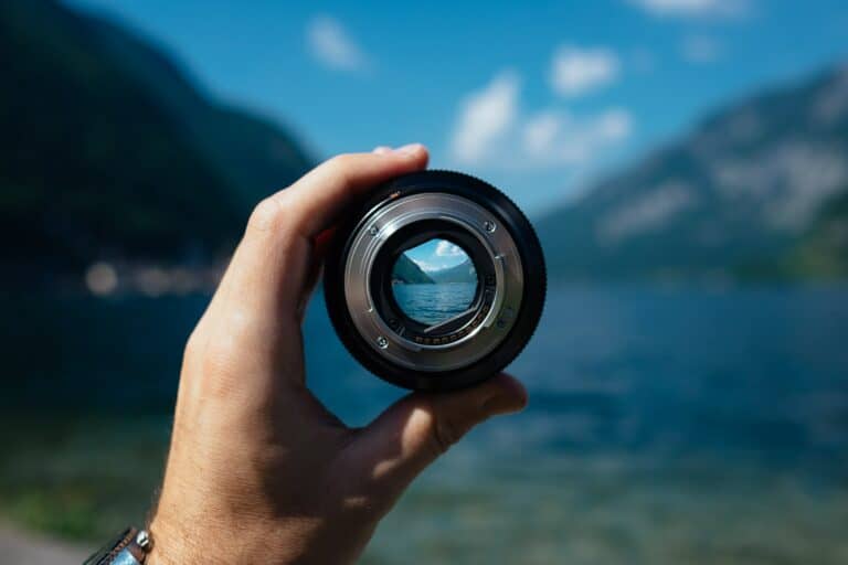 An image of a lake with a white hand holding a magnifying camera lens