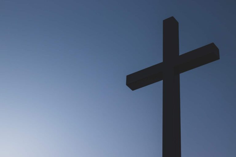 A wooden cross is set against a blue sky