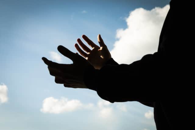 An image of open hands pointed toward the sky