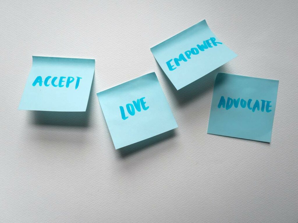 A picture of post-it notes with the words accept, love, empower, advocate written on them