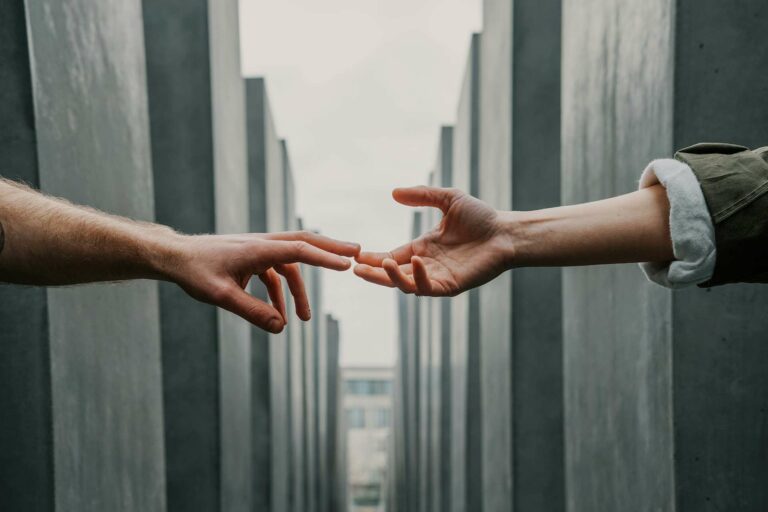 A hand of one person reaching for another person.