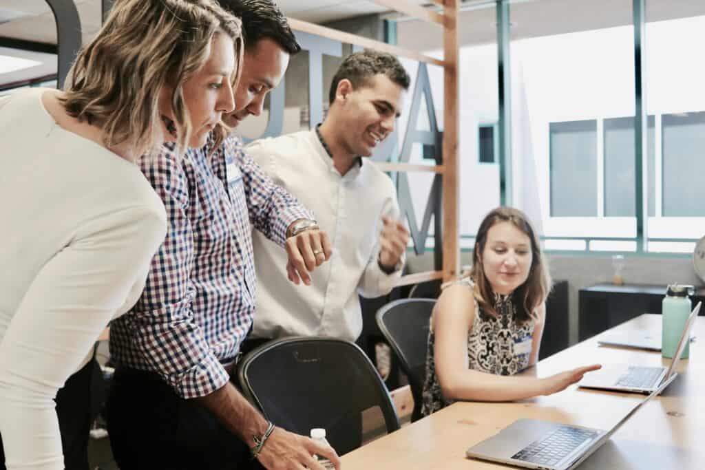 A group of men and women stand around a computer screen.