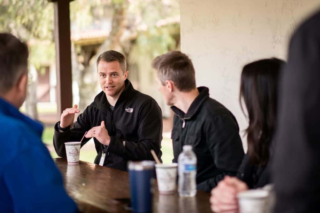 A man is talking to a small group around a table